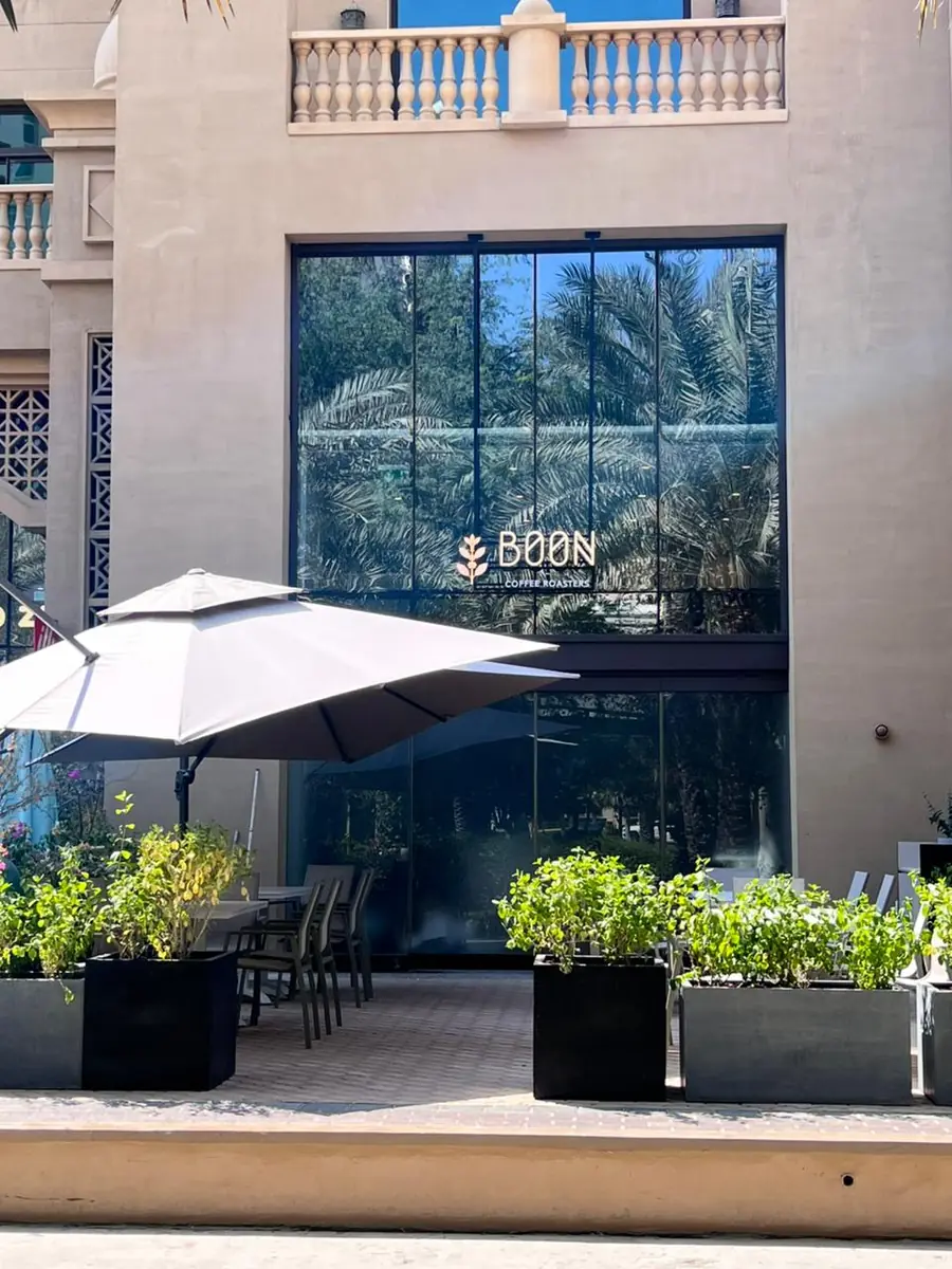Boon's glass storefront at Golden Mile 2 with an umbrella and plants